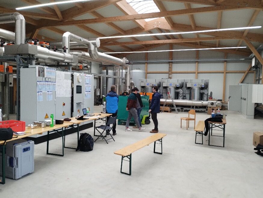 Halle der Energiezukunft mit provisorischer Messwarte, Biertischen und Laptops