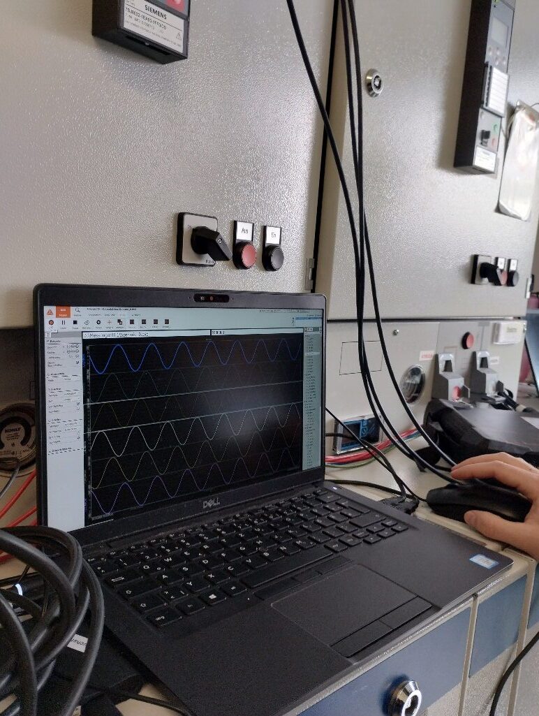 Laptop mit Messkurven vor einem Schaltschrank